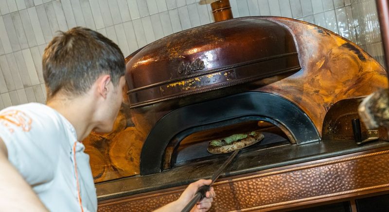 Our pizzaiolo taking a pizza out of the oven